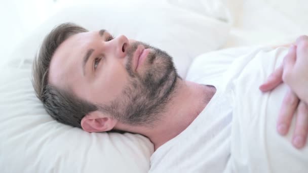ベッドで考える魅力的なひげの若い男 — ストック動画