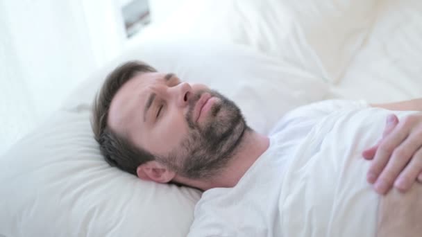 Kranker junger Mann mit Bart hat Zahnschmerzen im Bett — Stockvideo