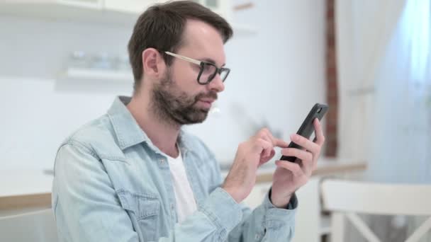 Fokuserat skägg ung man med hjälp av Smartphone i Office — Stockvideo