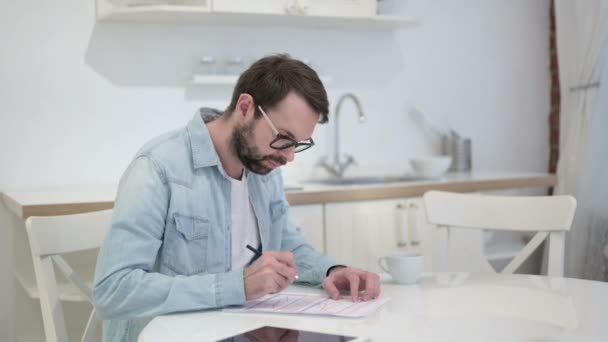 Enfocado barba joven escribiendo en papel en la oficina — Vídeos de Stock