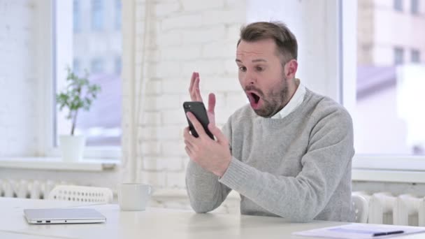Kreativer Mann verärgert über Verlust am Smartphone bei der Arbeit — Stockvideo