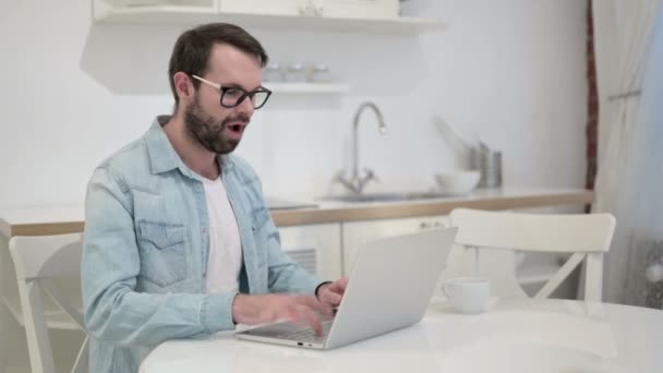 Överraskad skägg ung man firar framgång på laptop i Office — Stockvideo