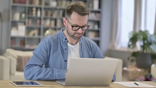 Сосредоточенный молодой человек работает над ноутбуком — стоковое видео