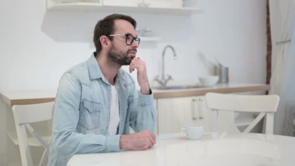 Задумчивый бородатый молодой человек мыслит в офисе — стоковое видео