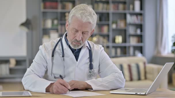 Senior Old Doctor gör pappersarbete på kliniken — Stockvideo