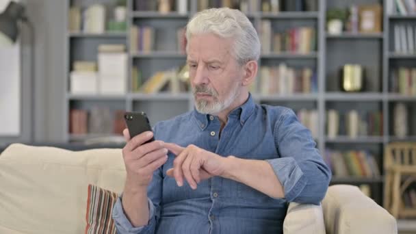 Portret van een oude man viert succes op de smartphone — Stockvideo