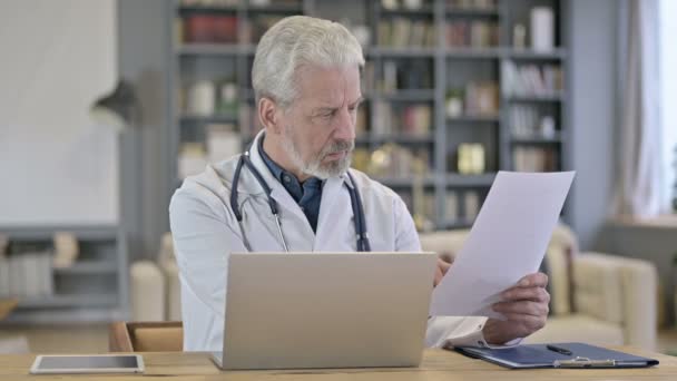 Старший врач читает медицинские документы в клинике — стоковое видео