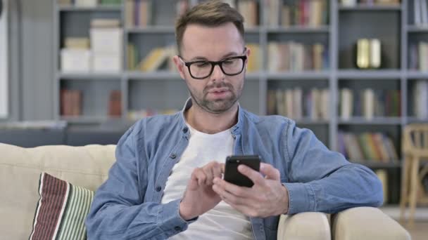 スマートフォンで成功を祝う若い男の肖像 — ストック動画