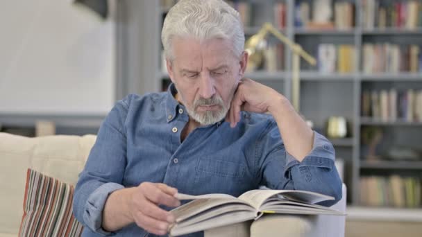 Portret van Senior Old Man Leesboek op Sofa — Stockvideo