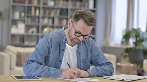 Unge man tänker och skriver på papper i Office — Stockvideo