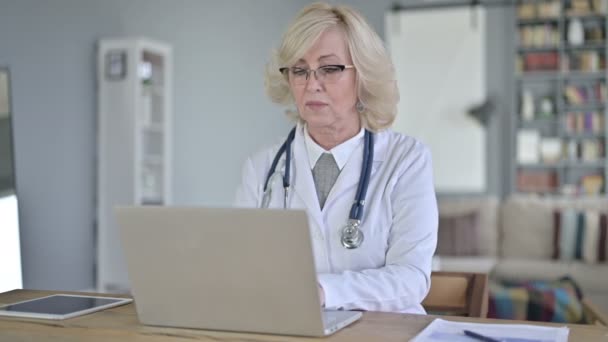 Vecchio medico femminile utilizzando il computer portatile per il lavoro — Video Stock