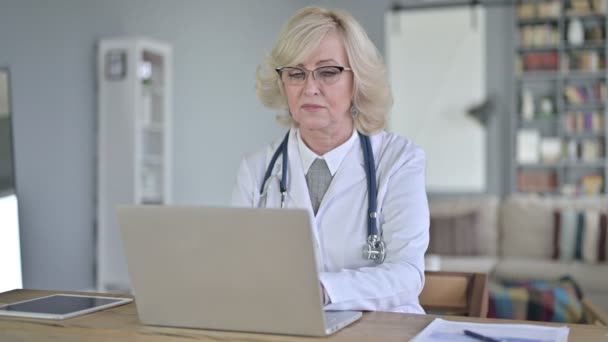 Vieux médecin féminin utilisant un ordinateur portable et souriant vers la caméra — Video