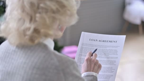 Visão traseira da mulher idosa leitura empréstimo acordo — Vídeo de Stock