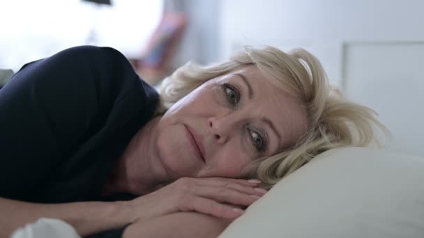 Ανήσυχη ηλικιωμένη γυναίκα σκέφτεται ενώ κοιμάται στο κρεβάτι — Αρχείο Βίντεο