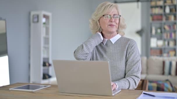 Krásná stará žena s bolestí krku v moderní kanceláři — Stock video