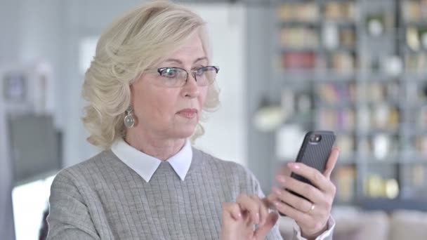 Portret starszej kobiety świętującej sukces na smartfonie — Wideo stockowe