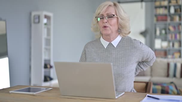 Усталая старуха с болями в спине в современном офисе — стоковое видео