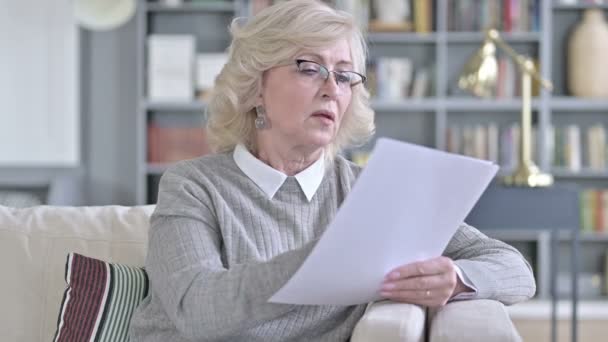 Alte Frau liest Dokumente auf dem Sofa — Stockvideo