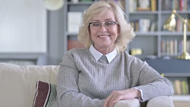 Splendida vecchia donna seduta sul divano e sorridente alla fotocamera — Video Stock