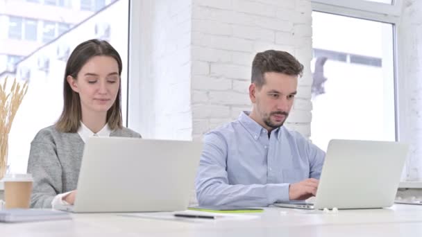 Aantrekkelijk creatief team werkt aan laptop en lacht naar de camera — Stockvideo