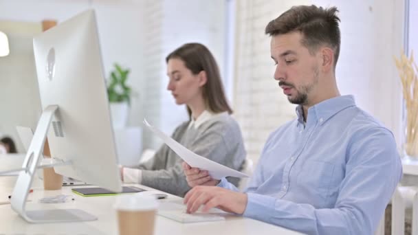 Homme créatif sérieux faisant de la paperasserie et utilisant le bureau — Video