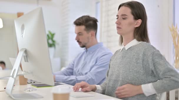 Cansada mujer creativa que tiene dolor de espalda en la oficina moderna — Vídeo de stock