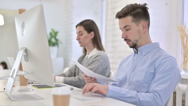 Creative Man Reading Documents και Εργασία στην επιφάνεια εργασίας — Αρχείο Βίντεο