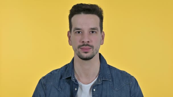 Retrato de joven guapo señalando dedo e invitando, fondo amarillo — Vídeos de Stock