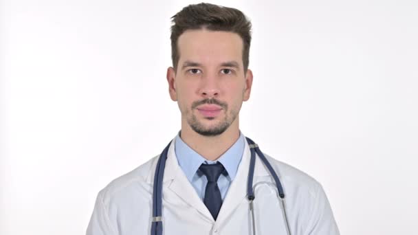 Портрет улыбающегося молодого врача, смотрящего на камеру, белый фон — стоковое видео