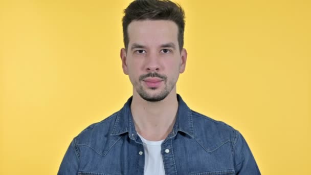 Портрет молодого человека, кладущего палец на губы, жёлтый фон — стоковое видео