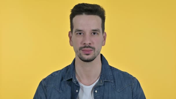 Retrato de un joven saludando a la cámara, fondo amarillo — Vídeos de Stock