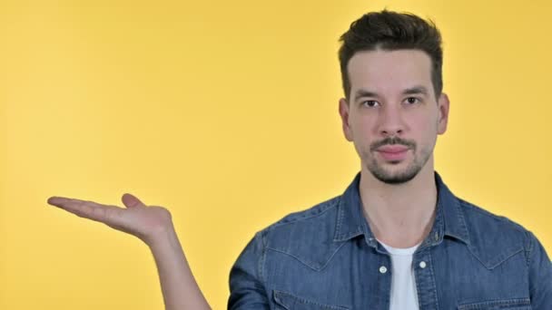 Retrato de Jovem segurando produto na mão, fundo amarelo — Vídeo de Stock