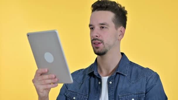 Портрет молодого человека в видеочате на планшете, жёлтый фон — стоковое видео