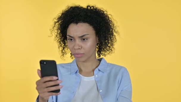 Портрет африканской женщины, реагирующей на потерю на смартфоне — стоковое видео
