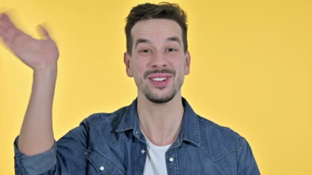 Retrato de un joven atractivo haciendo video chat, fondo amarillo — Vídeos de Stock