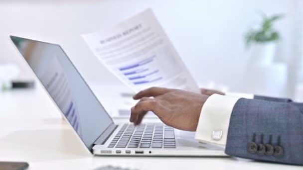 Close up of Hands of African Man reading Documents and working on Laptop — Stock video