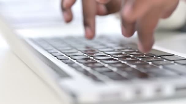 Vue de face des doigts de l'homme africain tapant sur le clavier de l'ordinateur portable  
