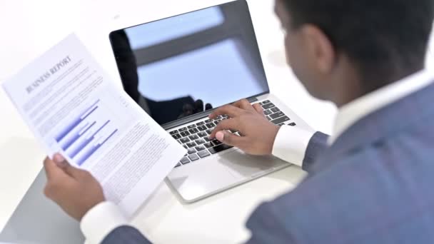 非洲商人阅读文件和在笔记本电脑上工作的背景图 — 图库视频影像