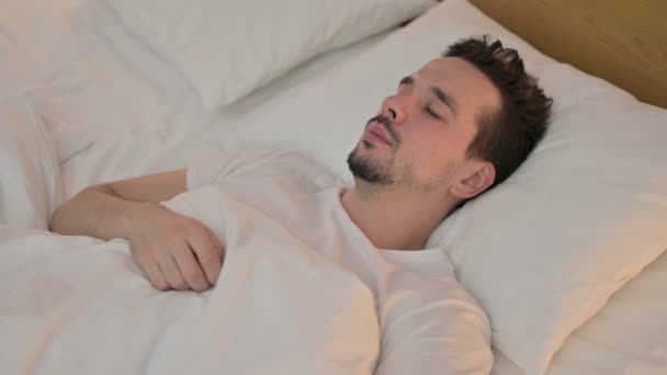 Όμορφος νεαρός άνδρας κοιμάται στο κρεβάτι — Αρχείο Βίντεο
