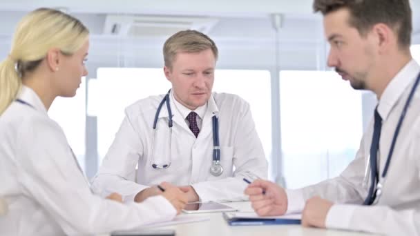 Сосредоточенный молодой доктор делает заметки и слушает старшего врача — стоковое видео