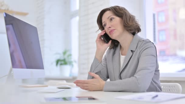 Creative Old Woman talking on Smartphone in Office Desk — Stock Video