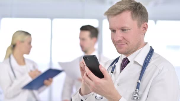 Портрет фокусованого лікаря за допомогою смартфона в офісі — стокове відео