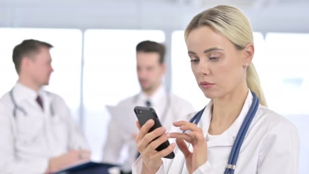 Portret poważnej lekarki korzystającej ze smartfona w biurze — Wideo stockowe