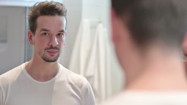 Jongeman glimlachend naar Camera In Mirror — Stockvideo