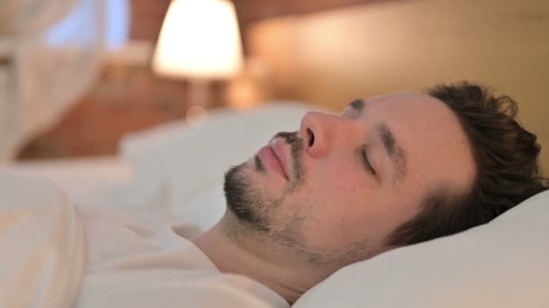 Портрет сбитого молодого человека, проснувшегося от сна в кровати — стоковое видео