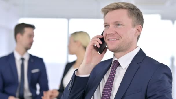 Porträt eines fokussierten Geschäftsmannes, der im Büro mit dem Smartphone spricht — Stockvideo