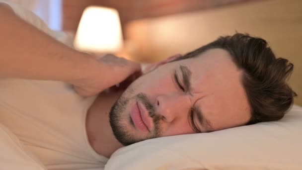 Портрет усталого молодого человека с болью в шее в постели — стоковое видео