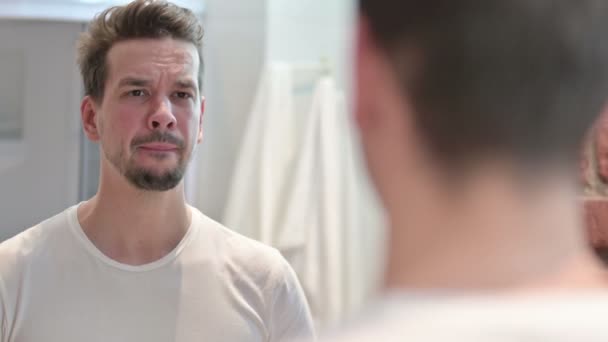 Joven molesto mirando la cara en el espejo — Vídeos de Stock