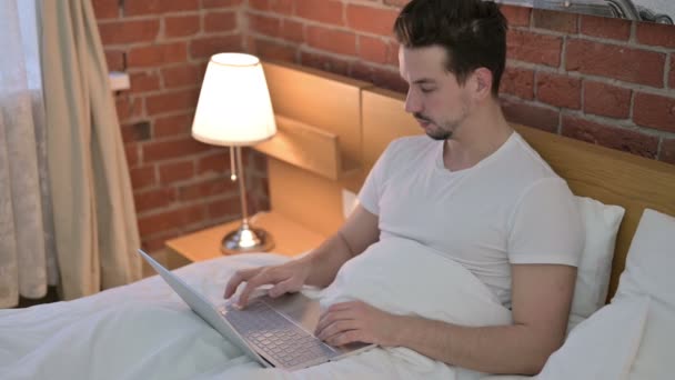 Hombre joven haciendo Video Chat en el ordenador portátil en la cama — Vídeos de Stock