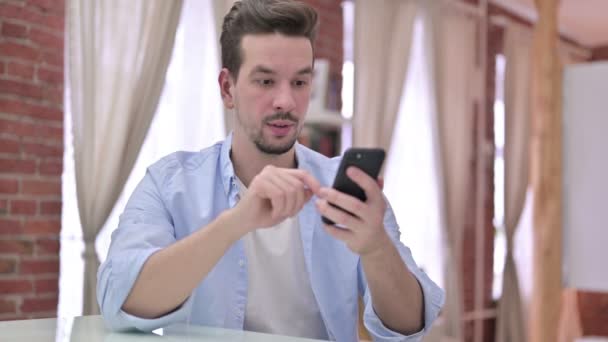 Joven celebrando en el Smartphone en casa — Vídeos de Stock